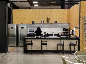 Cozinha compartilhada com geladeiras, bancada e banquetas na Aldeia Coworking