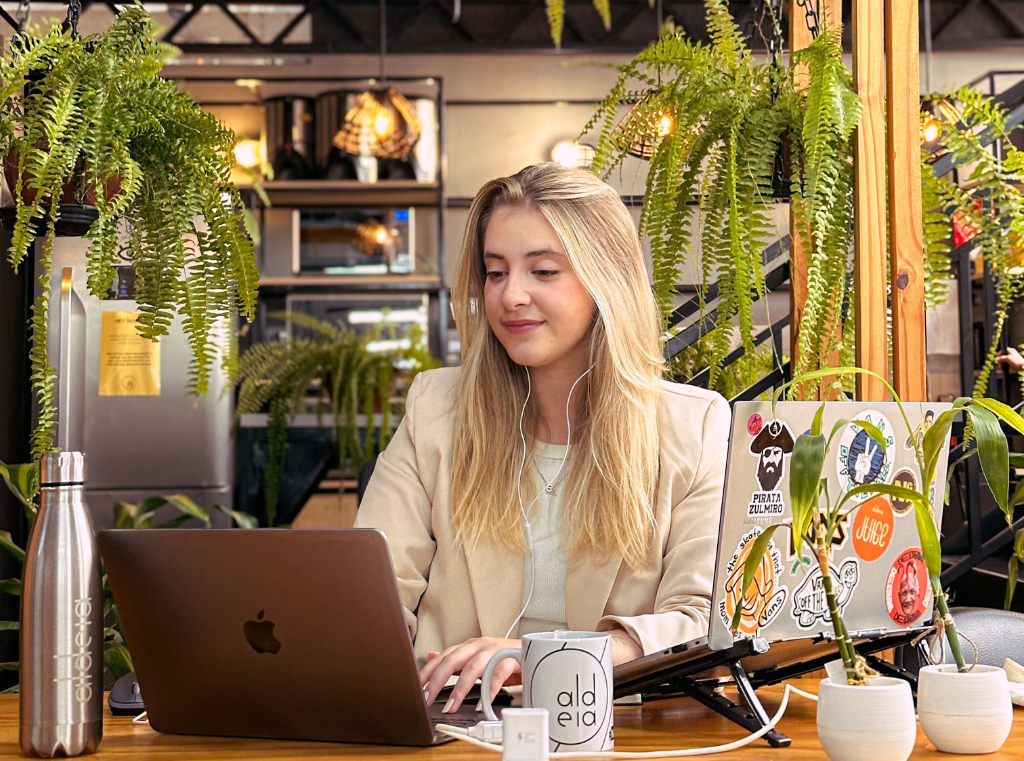 Na Aldeia Coworking em Curitiba, profissional em mesa de trabalho cercada de plantas