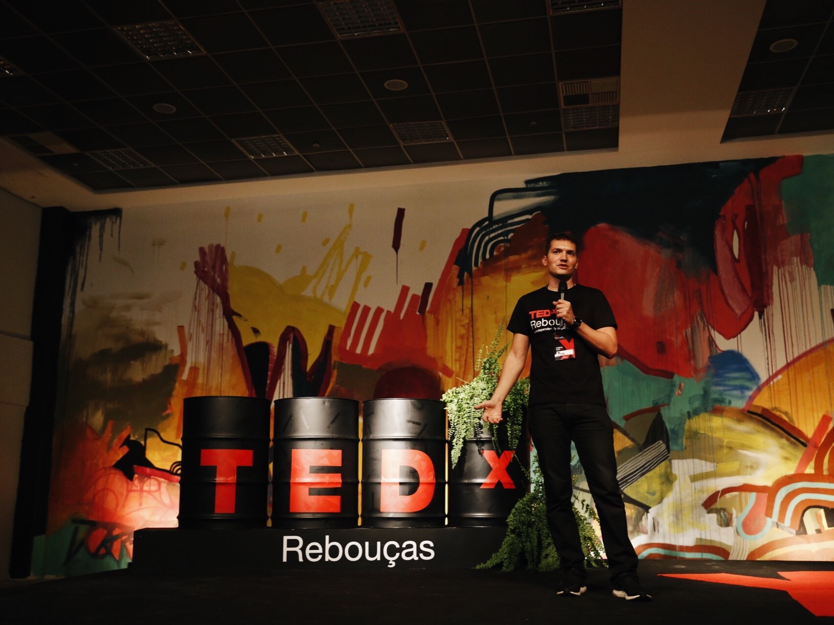Palco do evento TEDx Reboucas na Aldeia Coworking Curitiba, com apresentador e plateia.